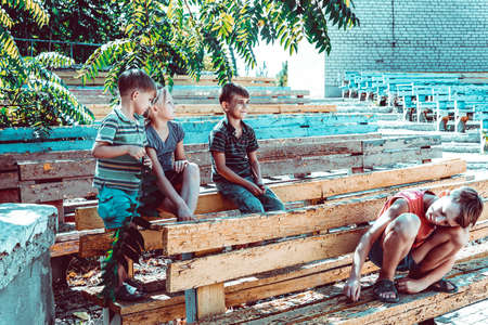 Orphaned children sit in an abandoned park on old benchesの写真素材