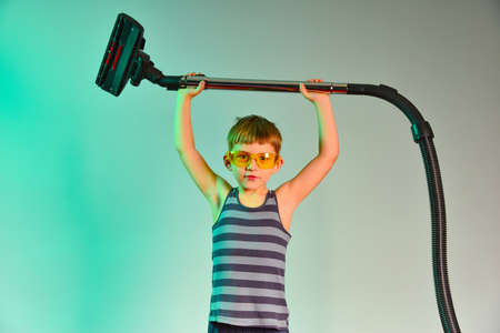 Cute baby raises the hose of the vacuum cleaner, photo in the studio.の写真素材