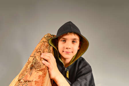 The boy holds a log on his shoulder, the guy carries firewood to light a fireの写真素材