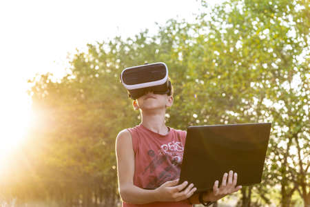 A boy on nature in virtual space, VR glasses, a forest, a laptop