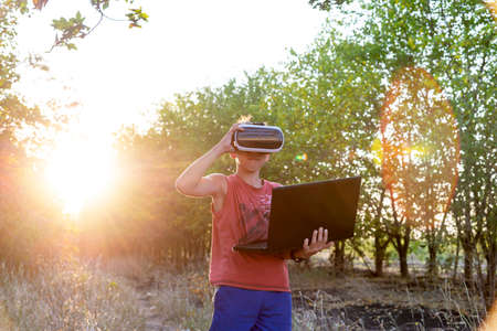 A boy on nature in virtual space, VR glasses, a forest, a laptop