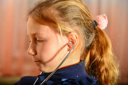 A girl holds a stethoscope in his hands and listens to the patient, home game at the doctor.の写真素材