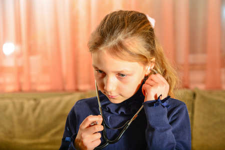 A girl holds a stethoscope in his hands and listens to the patient, home game at the doctor.の写真素材