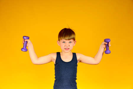 Mahi to the sides with dumbbells boy on a yellow background.