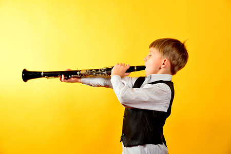 A little boy in a suit plays the clarinet.の写真素材