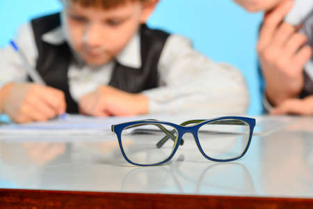 Glasses for sight against the background of children making lessons in school.の写真素材