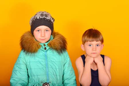 A girl in winter clothes and a boy in summer clothes are standing nearby.