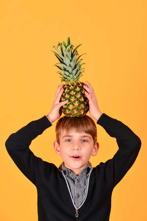 The boy holds a pineapple on his head, on a yellow background.の写真素材