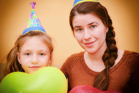 Mother and daughter on holiday with balloons in a cap with the inscription Happy Birthday.