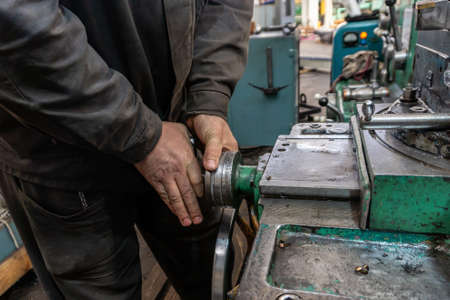 The hand of the machine operator creates a mechanical switch on the lathe