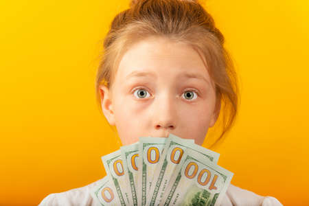 Surprised and joyful girl holds dollars in their hands and covers their face