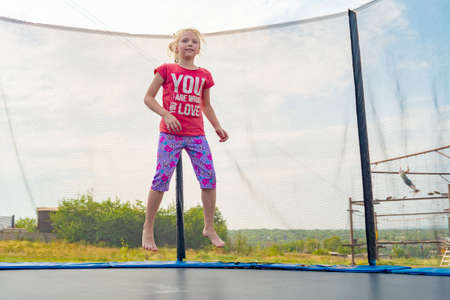 Athletic girl in a red T-shirt jumping on a trampolineの写真素材