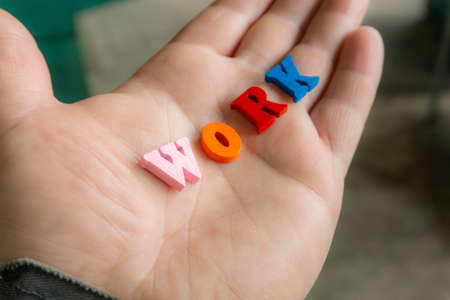 Multi-colored letters word work on a man's hand