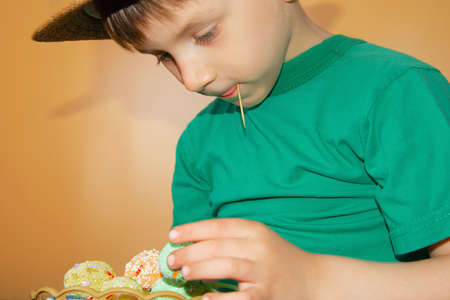 A boy in a straw hat holds painted Easter eggs in his hand.
