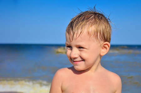 Portrait of a boy on the sea against the blue sky