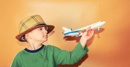The boy in a straw hat holds a passenger plane, the concept of freedom and travel