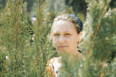 Portrait of a woman in the park on the background of natural leaves and branches
