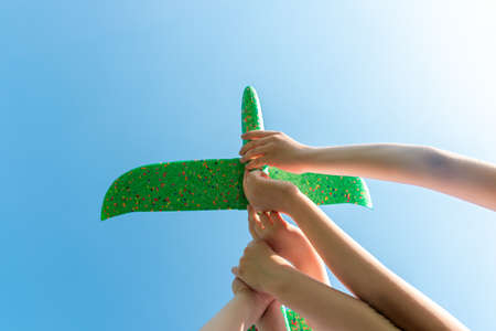 Children hold the plane with their hands against the blue skyの写真素材