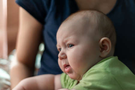 Portrait of a child close-up, little happy child in the arms of mom.