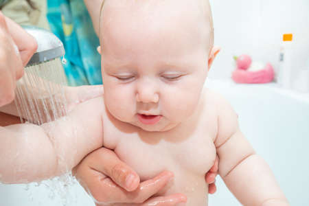 A small child in the shower, bathing a newborn girl, water procedures for a child; clean hygiene and...