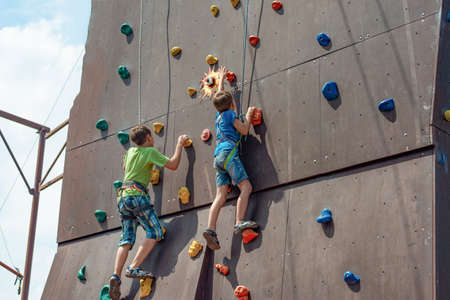 Two small climbers conquer the summit of an artificial mountain in a sports amusement park.の写真素材