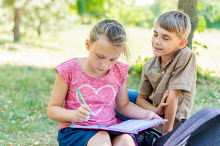 The boy and the girl are engaged in education, the girl writes in a notebook, and the boy tells her.の写真素材