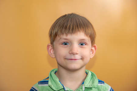 Portrait of a boy on a beige background, a joyful child looks into the camera.