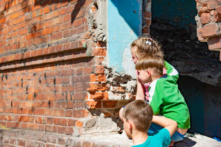 Three children in a destroyed house are hiding from military conflicts, refugee children have suffered from the destruction of terrorist acts of violence. Submission photo.の写真素材