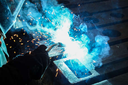 The worker is engaged in carrying out close-up welding work with the help of electric arc welding at...