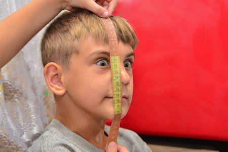 A person measures another's face with a centimeter. The concept of hypocrisy, conviction, greed of people.の写真素材