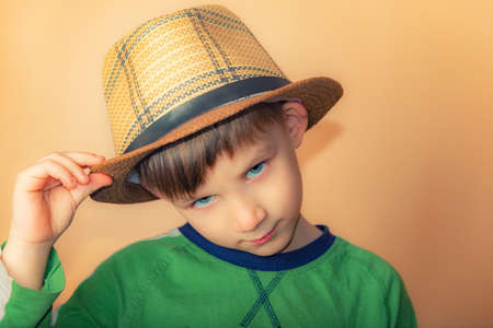A boy in a straw hat conveys a greeting, a portrait of a child on a beige background.の写真素材