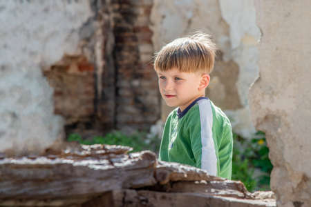 Poor orphans against the background of destroyed buildings, the concept of the life of street children. Staged photo.の写真素材