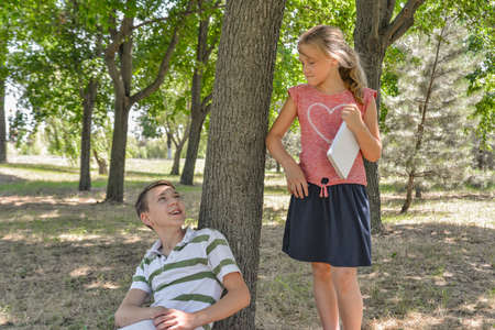 A boy and a girl do their homework in the park and get ready for school together.の写真素材