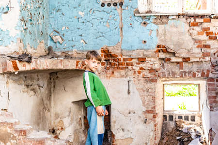 Orphaned children, poor child standing in a destroyed and abandoned building, staged photo.の写真素材