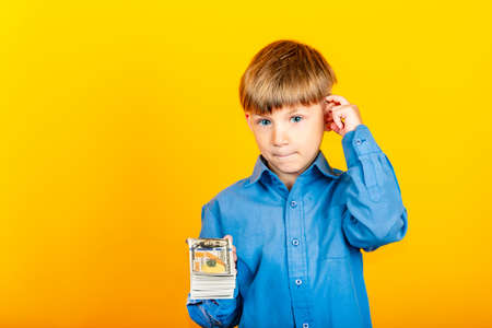 A small child with dollar bills, a boy holding a pack of dollar bills and offering it to you.の写真素材