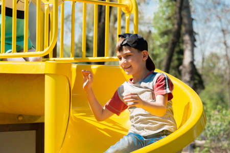 A child on a sports playground is riding on a hill, having fun during the summer holidays.の写真素材