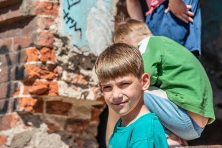 Poor orphans against the background of destroyed buildings, the concept of the life of street children. Staged photo.の写真素材