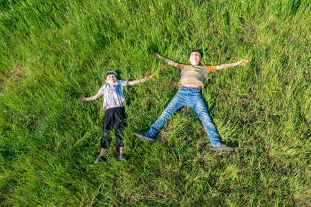 Two boys are lying on the grass, top view of happy and joyful friends.の写真素材