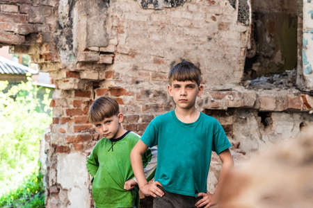 Two sad and unhappy brothers in a destroyed and abandoned building, staged photo.の写真素材