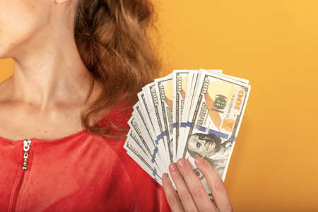 girl holds money in her hand and covers her face with dollars