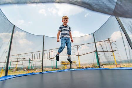 The boy jumps on a trampoline in an amusement park, performing various stunts.の写真素材