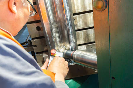 The worker controls the remote control on a cnc machine for milling and manufacturing the product.
