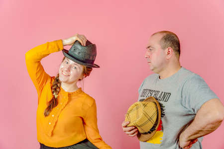 A man and a woman in a straw hat on a red background posing for the camera in the studio.
