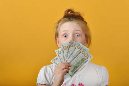 Surprised and joyful girl covers her face with money.