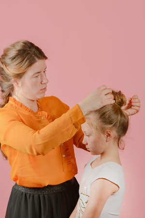 Woman make-up artist doing fashionable hairstyle to little girlの写真素材
