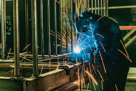 The welder assembles the metalwork at the enterprise by welded joints.
