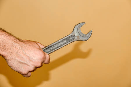 Wrench in mans male hand, on a yellow background.の写真素材