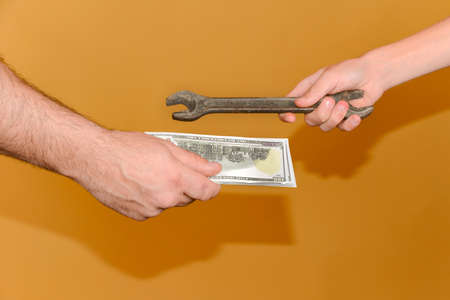 A wrench and money in the hands of people making a deal.の写真素材