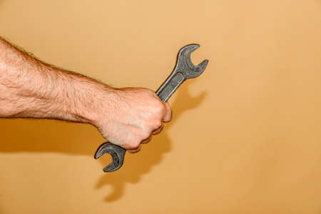 Wrench in mans male hand, on a yellow background.の写真素材