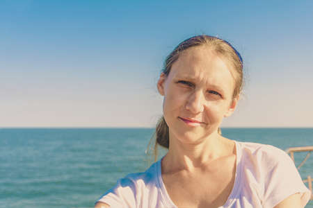 Portrait of a girl in a blue scarf, close-up on a background of the sea.